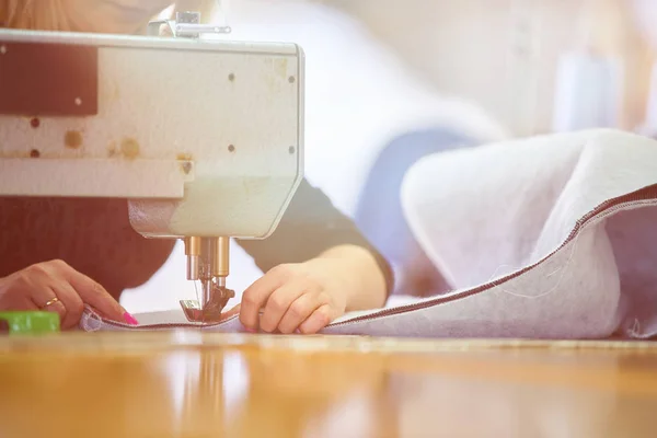 Seamstress or worker in a factory sewing with a industrial sewing machine