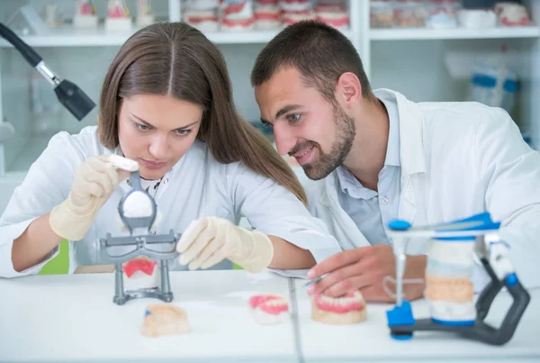 Takma diş, ağız hijyeni. Takma diş, takma diş, bir çalışma ve diş araçları içeren bir tablo üzerinde çalışırken protez eller.