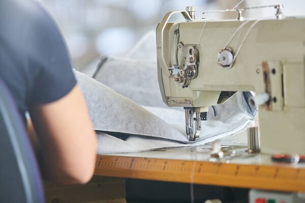 Seamstress or worker in a factory sewing with a industrial sewing machine, she is very accurate