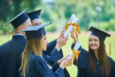Eğitim, mezuniyet ve halk konsepti. Havan topu ve diplomalı bekarlık elbisesi giyen bir grup mutlu uluslararası öğrenci.