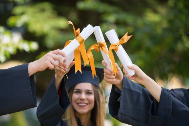 Eğitim, mezuniyet ve halk konsepti. Havan topu ve diplomalı bekarlık elbisesi giyen bir grup mutlu uluslararası öğrenci.