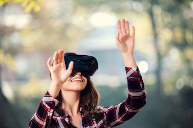 Güzel kız parkta eğleniyor VR kulaklık dışında kullanarak