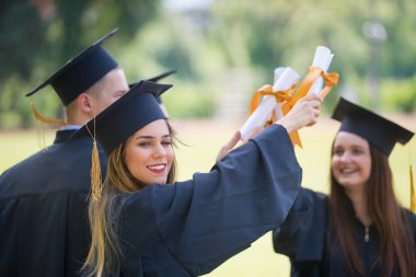 Eğitim, mezuniyet ve halk konsepti. Havan topu ve diplomalı bekarlık elbisesi giyen bir grup mutlu uluslararası öğrenci.