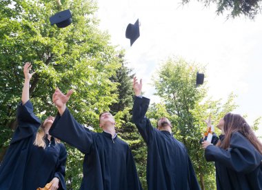 Eğitim, mezuniyet ve halk konsepti. Havan topu ve diplomalı bekarlık elbisesi giyen bir grup mutlu uluslararası öğrenci.