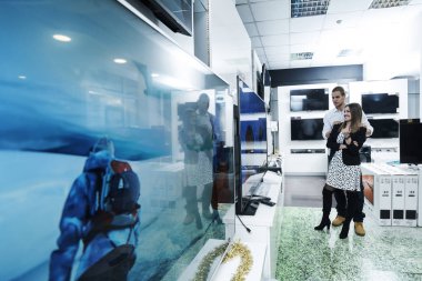 Genç çift tüketici elektroniği depolamak en son dizüstü bilgisayar, televizyon, cep, arıyor ve fotoğraf makinesi