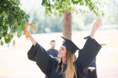 Eğitim, mezuniyet ve halk konsepti. Havan topu ve diplomalı bekarlık elbisesi giyen bir grup mutlu uluslararası öğrenci.