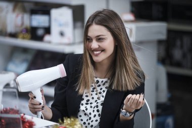 Saç bakım. Güzel uzun saçlı kadın elektronik mağazasında saç kurutma