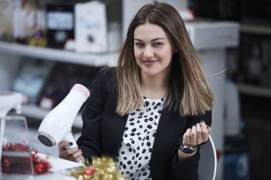 Saç bakım. Güzel uzun saçlı kadın elektronik mağazasında saç kurutma