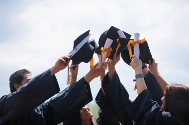Eğitim, mezuniyet ve halk konsepti. Havan topu ve diplomalı bekarlık elbisesi giyen bir grup mutlu uluslararası öğrenci.