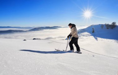 Ski touring man reaching the top at sunrise in Swiss Alps. clipart