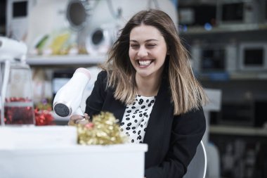 Saç bakım. Güzel uzun saçlı kadın elektronik mağazasında saç kurutma