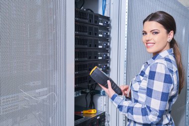 Beyaz sunucu odası açık server raf yanındaki tamirhanede sunucu üzerinde çalışan kadın teknisyeni