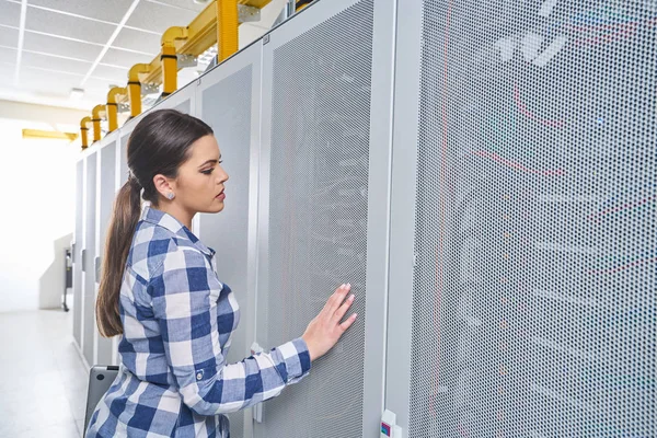female technician working on server maintenance in white server room
