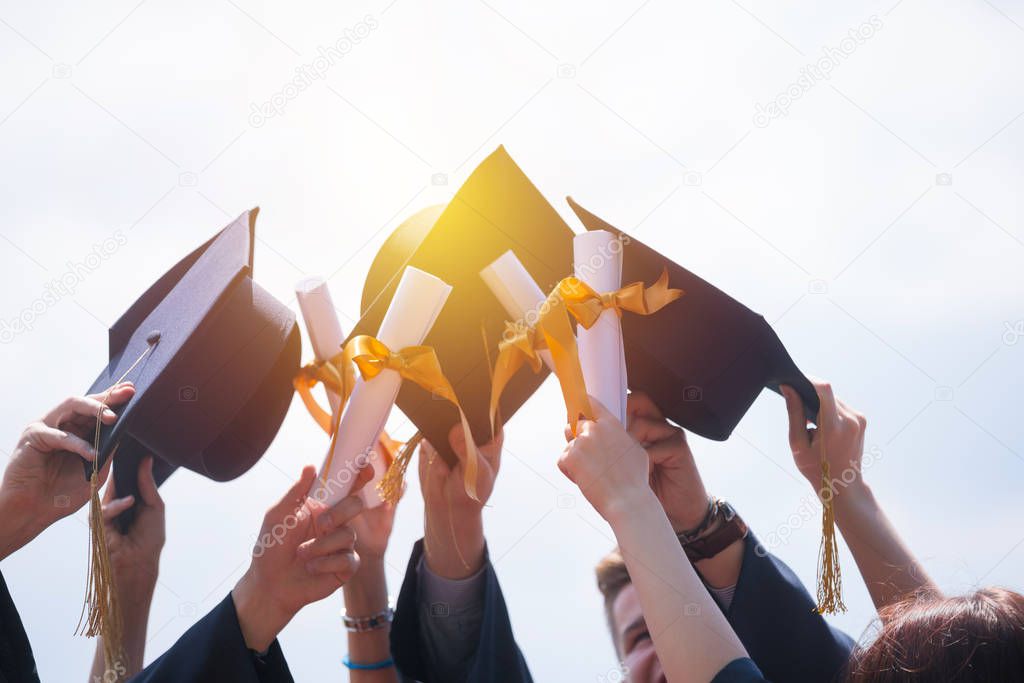 education, graduation and people concept - group of happy international students in mortar boards and bachelor gowns with diplomas