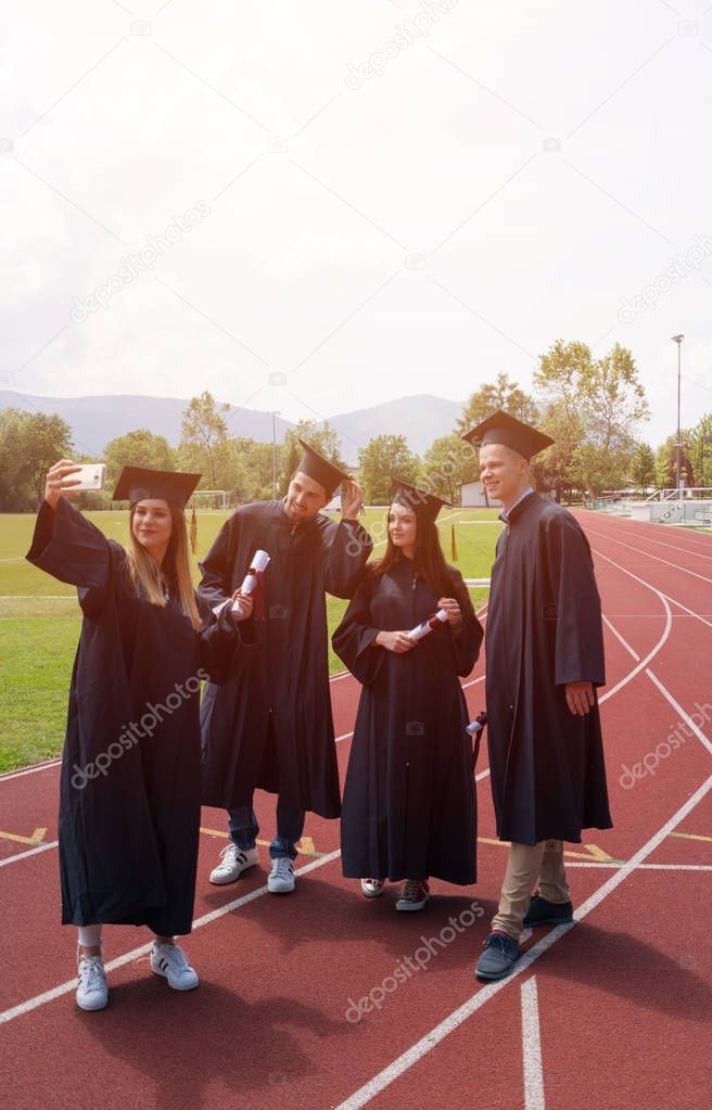 education, graduation and people concept - group of happy international students in mortar boards and bachelor gowns with diplomas