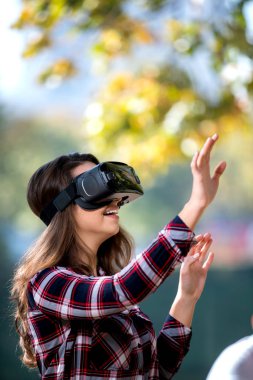 Güzel kız parkta eğleniyor VR kulaklık dışında kullanarak