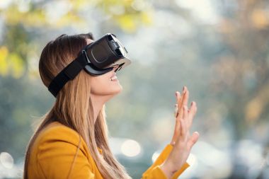 Güzel kız parkta eğleniyor VR kulaklık dışında kullanarak