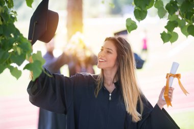 Eğitim, mezuniyet ve halk konsepti. Havan topu ve diplomalı bekarlık elbisesi giyen bir grup mutlu uluslararası öğrenci.