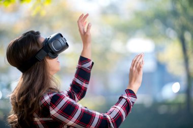 Güzel kız parkta eğleniyor VR kulaklık dışında kullanarak