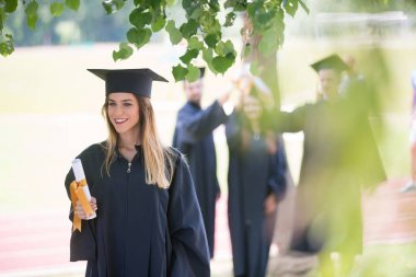 Eğitim, mezuniyet ve halk konsepti. Havan topu ve diplomalı bekarlık elbisesi giyen bir grup mutlu uluslararası öğrenci.