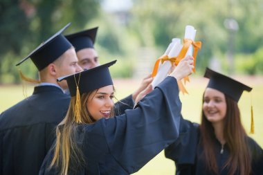 Eğitim, mezuniyet ve halk konsepti. Havan topu ve diplomalı bekarlık elbisesi giyen bir grup mutlu uluslararası öğrenci.