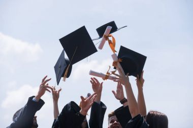 Eğitim, mezuniyet ve halk konsepti. Havan topu ve diplomalı bekarlık elbisesi giyen bir grup mutlu uluslararası öğrenci.