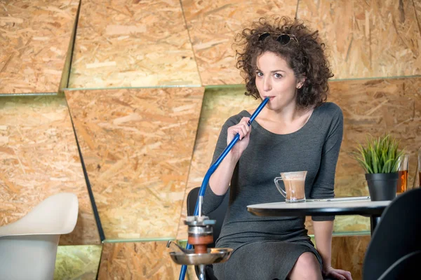 Chica hipster de moda disfrutando de la cachimba en una cafetería moderna — Foto de Stock