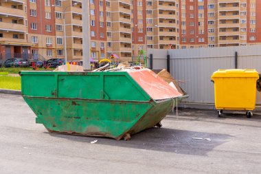 Çok katlı bir binanın arka planında kırık tuğlalar olan inşaat atığı konteynırı