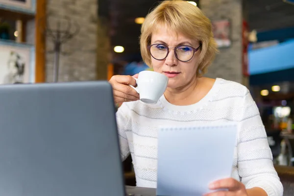 Una mujer con un portátil trabaja en un café en la oficina, es freelancer y un hombre de negocios — Foto de Stock