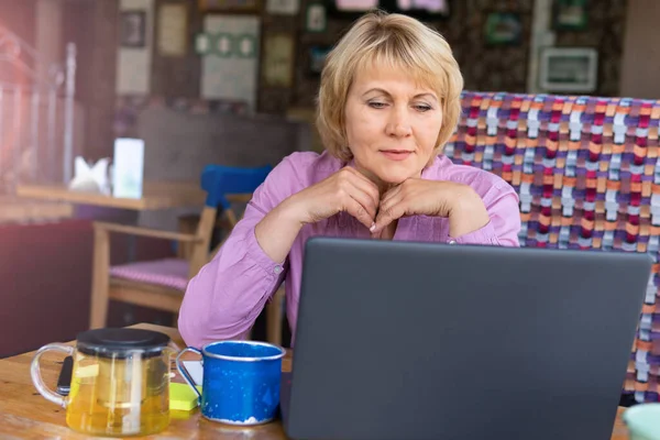 Una mujer con un portátil trabaja en un café en la oficina, es freelancer . — Foto de Stock