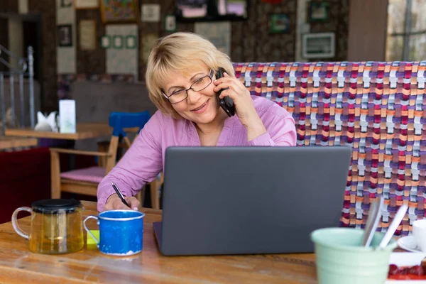 Una mujer con un portátil trabaja en un café en la oficina, es freelancer . — Foto de Stock