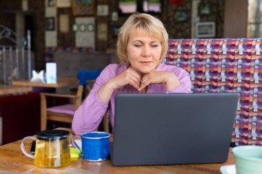 Ofisteki bir kafede dizüstü bilgisayarı olan bir kadın, serbest çalışan ve iş adamıdır.