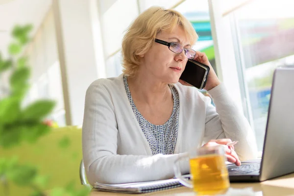 A woman with a laptop works in a cafe in the office, she is a freelancer and a businessman