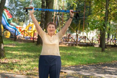 Yaşlı bir kadın parktaki sopayla kuzeye doğru yürür.