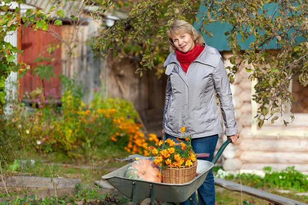 Perempuan di kebun memanen sayur-sayuran, buah-buahan di latar belakang rumah dan pohon . — Stok Foto