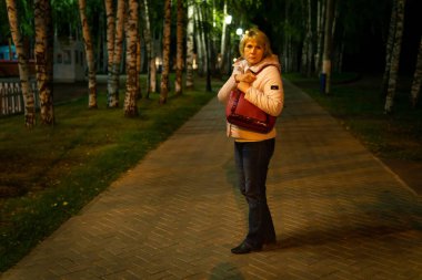 Bir kadın gece boyunca yürür Park sokak lambalarının ışığında.