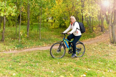 Şehir parkında bisiklet süren bir kadın var.