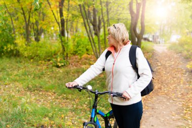 Şehir parkında bisiklet süren bir kadın var.