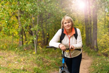 Şehir parkında bisiklet süren bir kadın var.