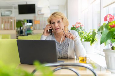 Bilgisayarlı bir kadın bir kafede, ofiste bir belgeye bakıyor.