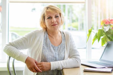 Bilgisayarlı bir kadın bir kafede, ofiste bir belgeye bakıyor.