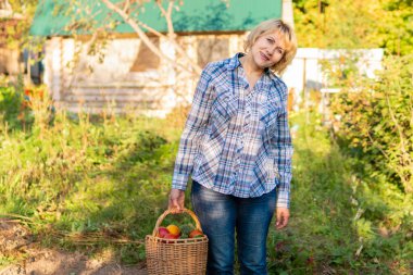 Bahçesinde sebze ve çiçeklerden oluşan bir yatakta çalışan bir kadın.