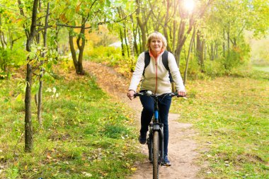 Şehir parkında bisiklet süren bir kadın var.