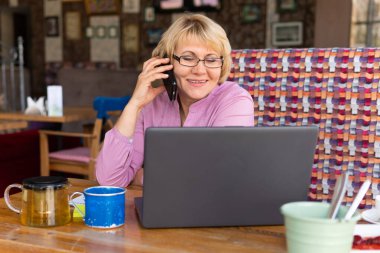 Bilgisayarlı bir kadın bir kafede, ofiste bir belgeye bakıyor.