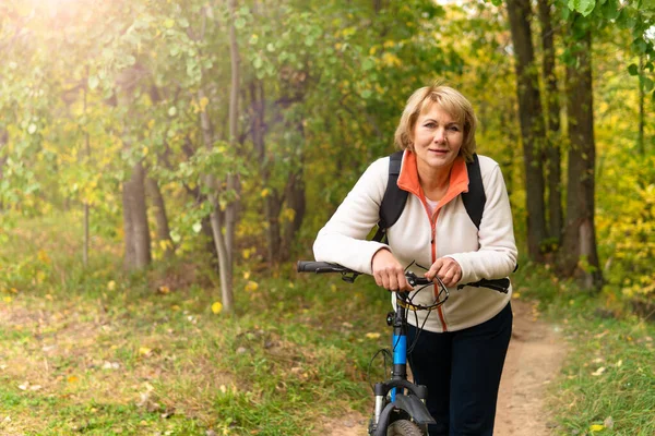 Şehir parkında bisiklet süren bir kadın var.