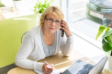 Bilgisayarlı bir kadın bir kafede, ofiste bir belgeye bakıyor.