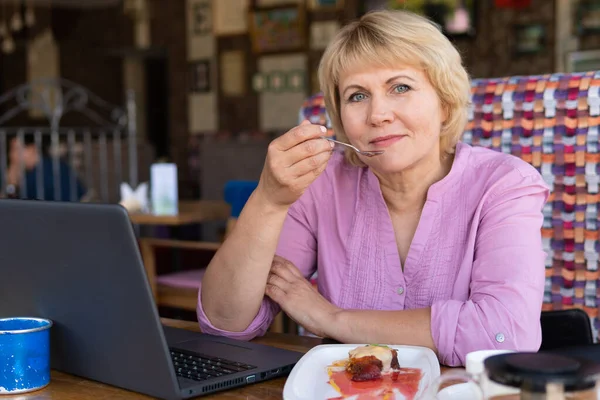 Женщина с ноутбуком работает в кафе, смотрит социальные сети . — стоковое фото
