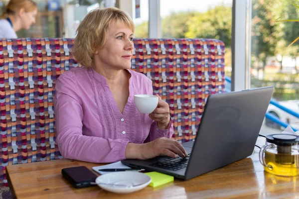 Женщина с ноутбуком работает в кафе, смотрит социальные сети . — стоковое фото
