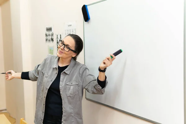 Een vrouwelijke ondernemer of docent die op een schoolbord schrijft met een uitwisbare presentatiemarkering in een vergaderzaal. — Stockfoto