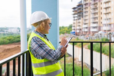 İnşaat alanında çalışan bir kadın müteahhit süreci kontrol ediyor..